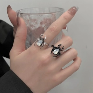 Detailed view of silver and black spider rings with white gemstones on model fingers
