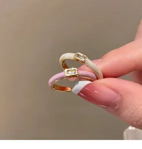 Detailed close-up of pink and white enamel rings with rectangular zircon on gold bands