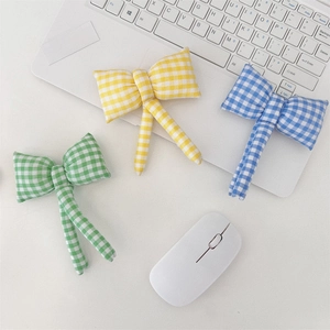 Detailed view of yellow, green, and blue plaid bow hair accessories on a white desk
