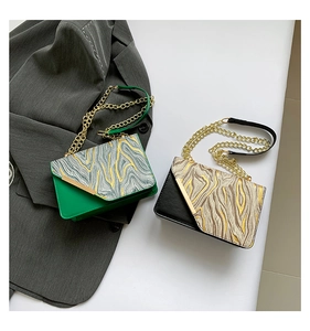 Detail of green and black stone pattern bags with gold chains on a grey blazer