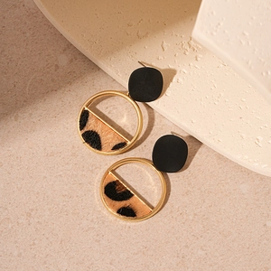 Detail of leopard print flocking and black matte geometric earrings on a stone base
