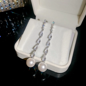Close-up of elegant silver tassel earrings with zircon water drops and white pearls