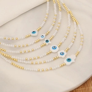 Evil eye beaded necklaces with heart and hamsa pendants on a white stone tray