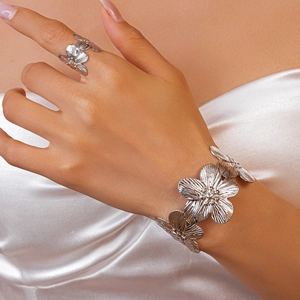 Close-up of silver metal floral ring and bracelet set with textured brushed petals