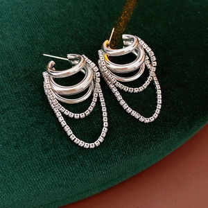 Détail de boucles d'oreilles à pompons en argent et zircons sur velours vert