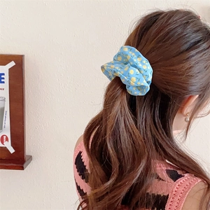 Detailed view of sky blue floral scrunchie with yellow flowers on a ponytail