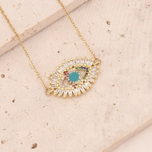 Detail of gold evil eye pendant with turquoise center and colorful zircon stones