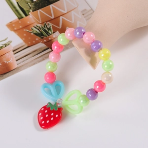 Colorful beaded kids bracelet with red strawberry charm and heart beads on a display stand
