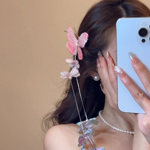 Detailed view of pink butterfly hair clip with pearl center and flower tassel on hair