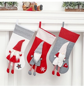 Close-up of three knitted Christmas stockings with 3D gnome dolls hanging on a fireplace