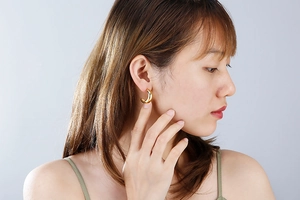 Close-up of golden C-shaped stainless steel earrings on female model for daily wear