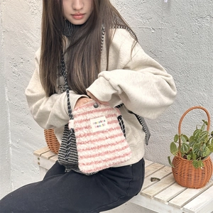 Detail of pink and white striped plush crossbody bag with woven strap on a model