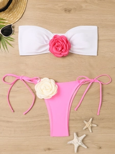 Detailed flat lay of pink and white bikini with 3D floral accents and side ties