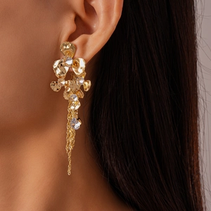 Detailed view of gold flower earrings with sparkling crystals and long metal tassels