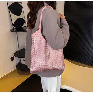 Detail einer pinkfarbenen Strass-Tragetasche mit Gittermuster an der Schulter des Models