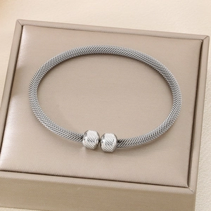 Close-up of silver mesh bracelet with spiral textured beads on champagne jewelry box