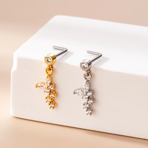 Detail of L-shaped nose studs in gold and silver finish with crystal butterfly pendants
