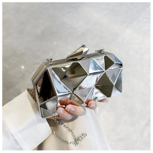 Detail of silver geometric mirror clutch with metallic faceted texture and chain