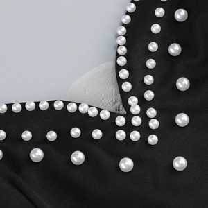 Detail of white pearls and mesh inserts on black dress fabric with beadwork textures
