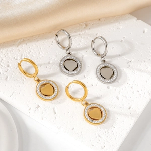 Détail de boucles d'oreilles cœur en acier doré et argenté avec zircons sur tissu en soie