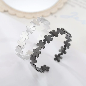 Detailed view of cutout daisy flower pattern on silver and black open cuff bracelets