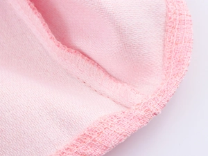 Detailed close-up of pink tweed fabric texture with high-quality stitching and neat edging