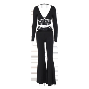 Detail of black two-piece set featuring cutout buckle straps on V-neck top and flared trousers