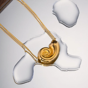 Macro view of gold shell pendant necklace on reflective water surface background