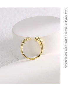 Dettaglio di un anello placcato oro minimalista su piedistallo con testo descrittivo