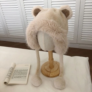 Detailed view of plush beige bear ear hat with brown lining on wooden mannequin