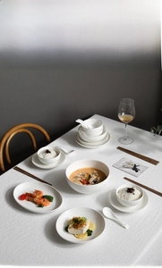 Detail of white ceramic tableware set with embossed textures in a lifestyle dining setting