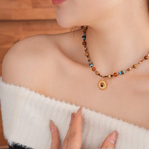 Macro detail of sun pendant with black stone and colorful beaded chain on neck