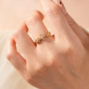 Close-up of a vintage-style gold ring with zircon flowers worn by a model in soft lighting