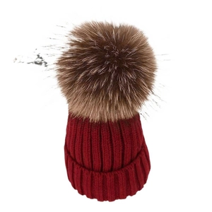 Winter chunky knit beanie in deep red featuring a large fluffy brown faux fur pom-pom