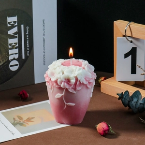 Detailansicht brennende rosa Kerze mit weißer Relief-Blumentextur auf der Oberseite