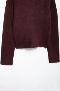 Détails du pull en maille bordeaux montrant la texture de l'ourlet et des poignets côtelés