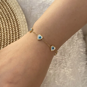 Golden bracelet featuring heart-shaped evil eye charms worn on wrist for a natural look