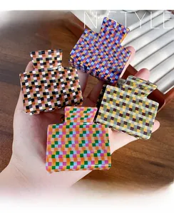 Close-up of four checkerboard square hair claws in vibrant colors for stylish hair styling