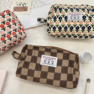 Detailed view of three corduroy makeup bags with floral and checkerboard patterns