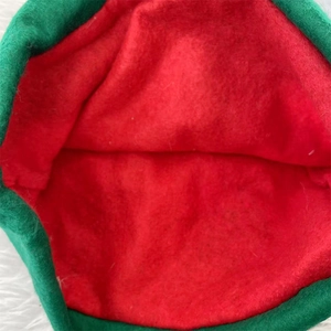 Gros plan sur la texture en feutre rouge et vert et les coutures du bonnet de lutin
