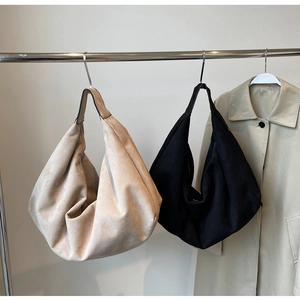 Detail of large frosted leather hobo bag hanging on rack showing texture and slouchy shape