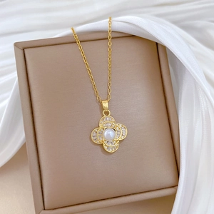 Detailed view of luxury gold clover pendant with white pearl and sparkling zircons