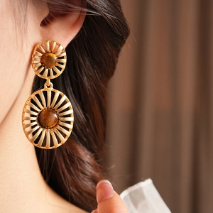 Detailed close-up of vintage gold tiger eye stone oval earrings on model's ear