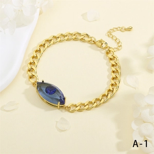 Nahaufnahme eines goldenen Gliederkettenarmbands mit blauem Evil-Eye-Anhänger und Karabinerverschluss