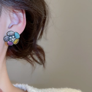 Detailed close-up of a sparkling five-petal flower stud earring with colorful zircon stones