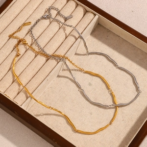 Detailed macro shot of 18K gold and S925 silver wavy necklaces on beige velvet jewelry box