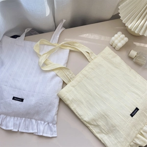 Detail of ruffled edges and textured fabric on minimalist canvas tote bags with logo