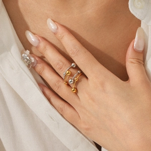Dual-layer stainless steel ring with gold and silver beads shown on a model's hand