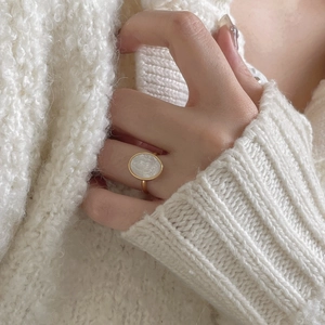Minimalist 925 silver golden ring with oval shell relief cameo on white knit background