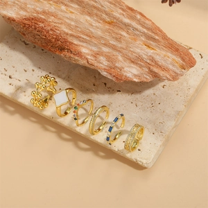 Set of six vintage gold square rings with colorful gemstones and pearls on stone base